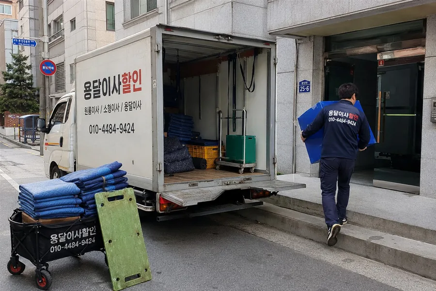 이사 현장에 준비된 운반 카트, 사다리, 포장 자재와 작업 차량